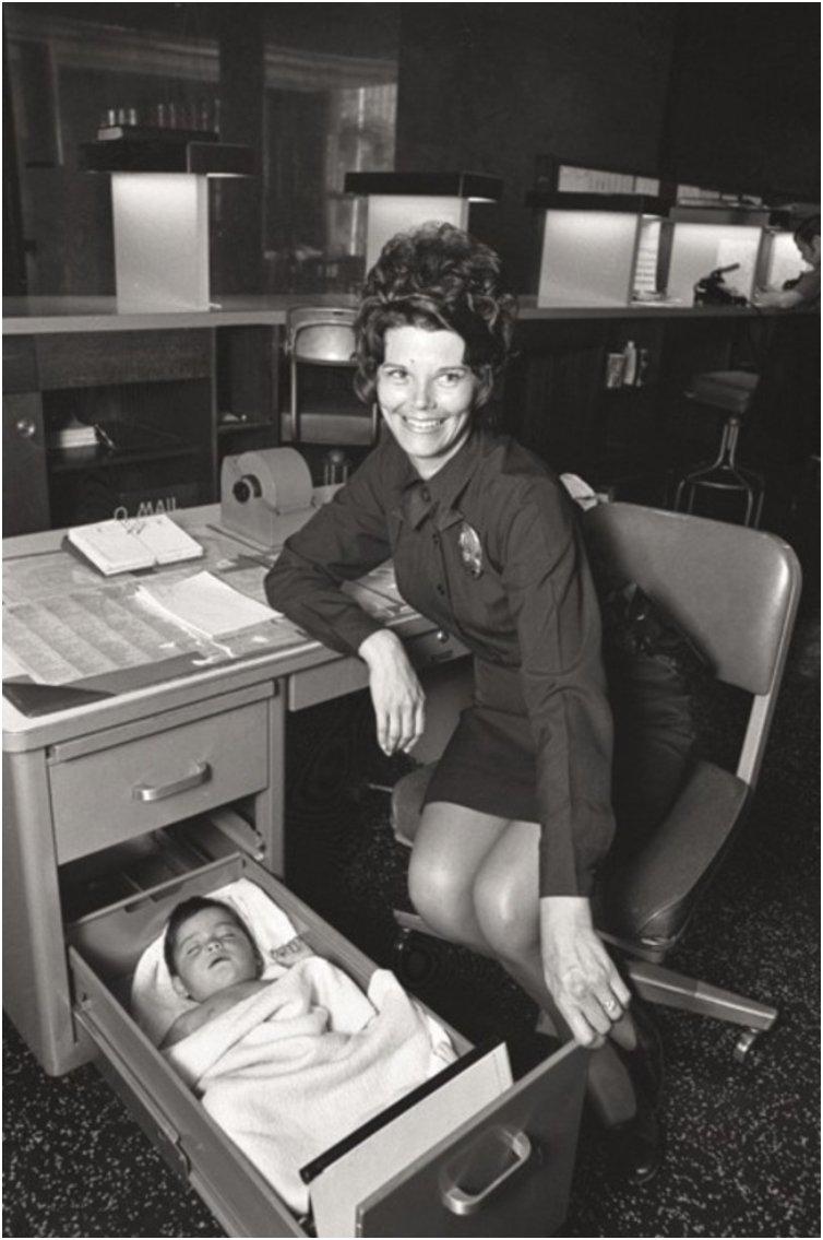 A Los Angeles Police Officer looks after an abandoned baby in the drawer of her desk. [1971]