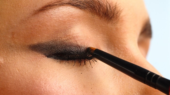 Closeup shot stylist drawing black arrows on the eyes of the f | Mamabee