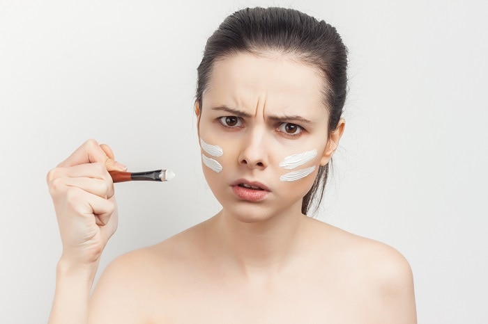 pretty woman with bare shoulders apply cream brush to face spa treatments | Mamabee