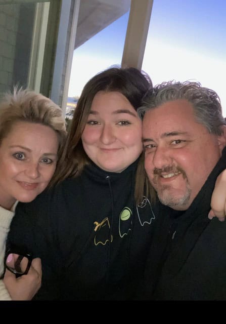 Three people posing for a selfie by a window, smiling at the camera.